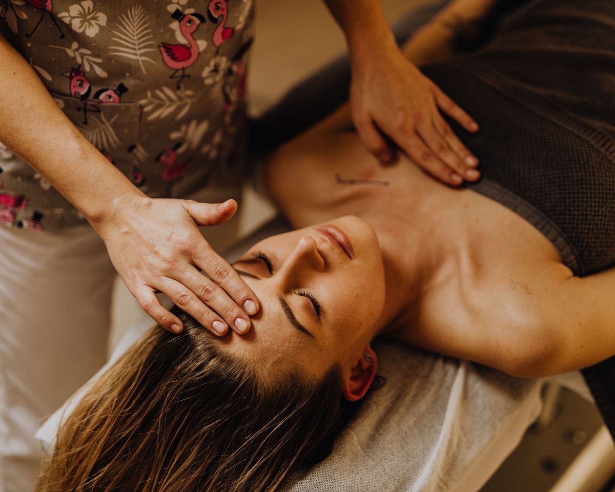 A therapist's hands resting either side of a client's head during cranial sacral work